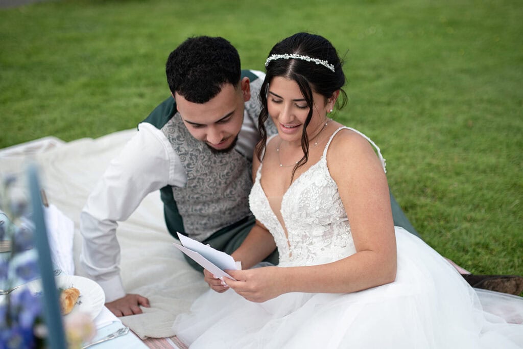 Hochzeitspaar liest gemeinsam ihre individuelle Hochzeits-Karte im Grünen